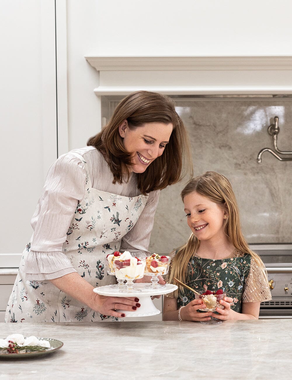 Woman and young girl in a kitchen preparing desserts together.