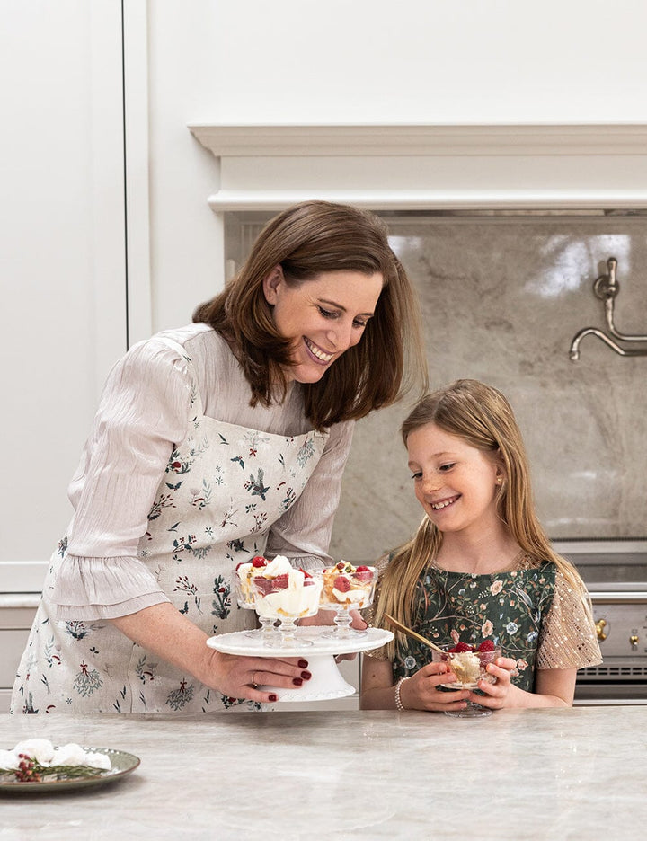 Woman and young girl in a kitchen preparing desserts together.