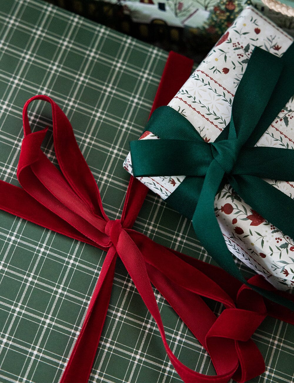 Gift wrapped in green paper with a red ribbon on a plaid surface