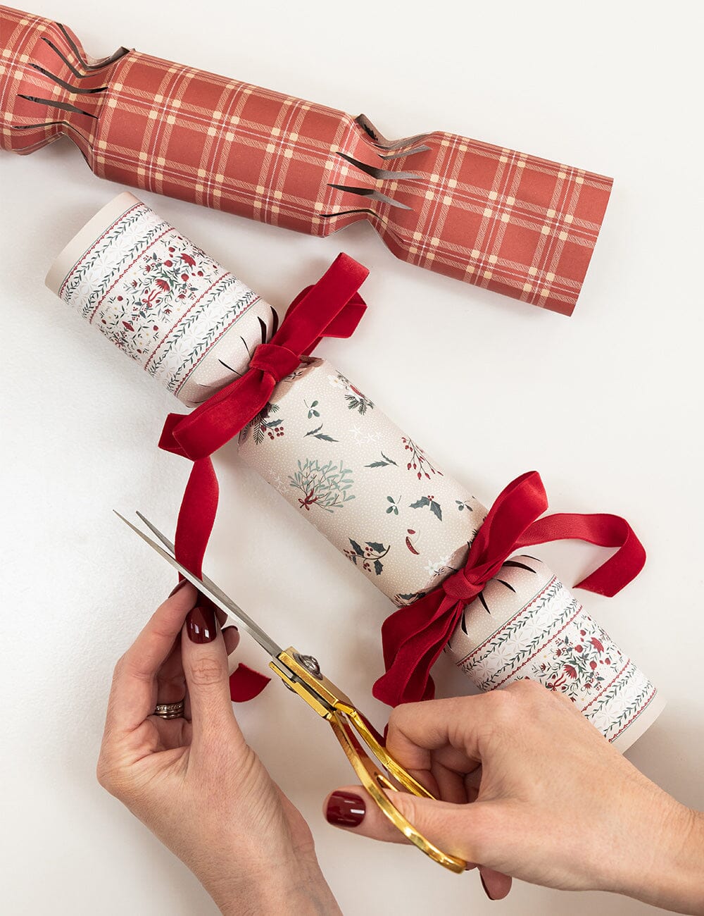 Decorative Christmas crackers with red ribbons and a pair of scissors on a white background