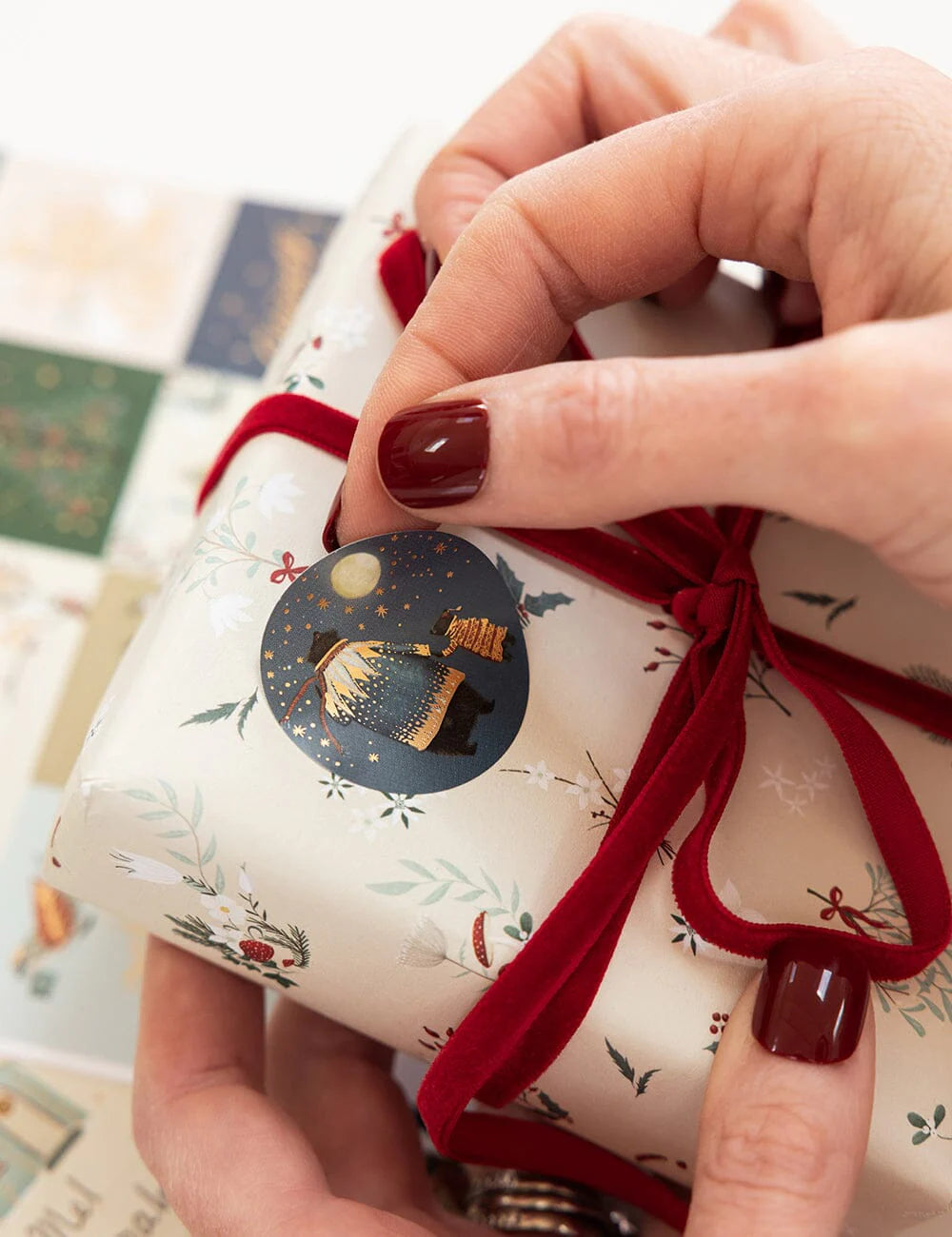 Hand holding a small wrapped gift with a red ribbon and festive design.
