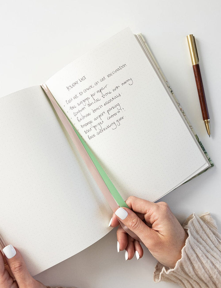 Open notebook with handwritten text on a light surface, accompanied by a pen.