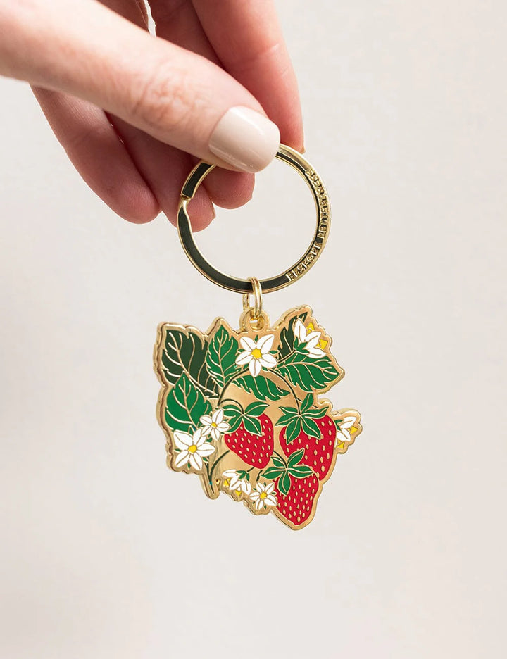 Keychain strawberry design held by a hand on a light background