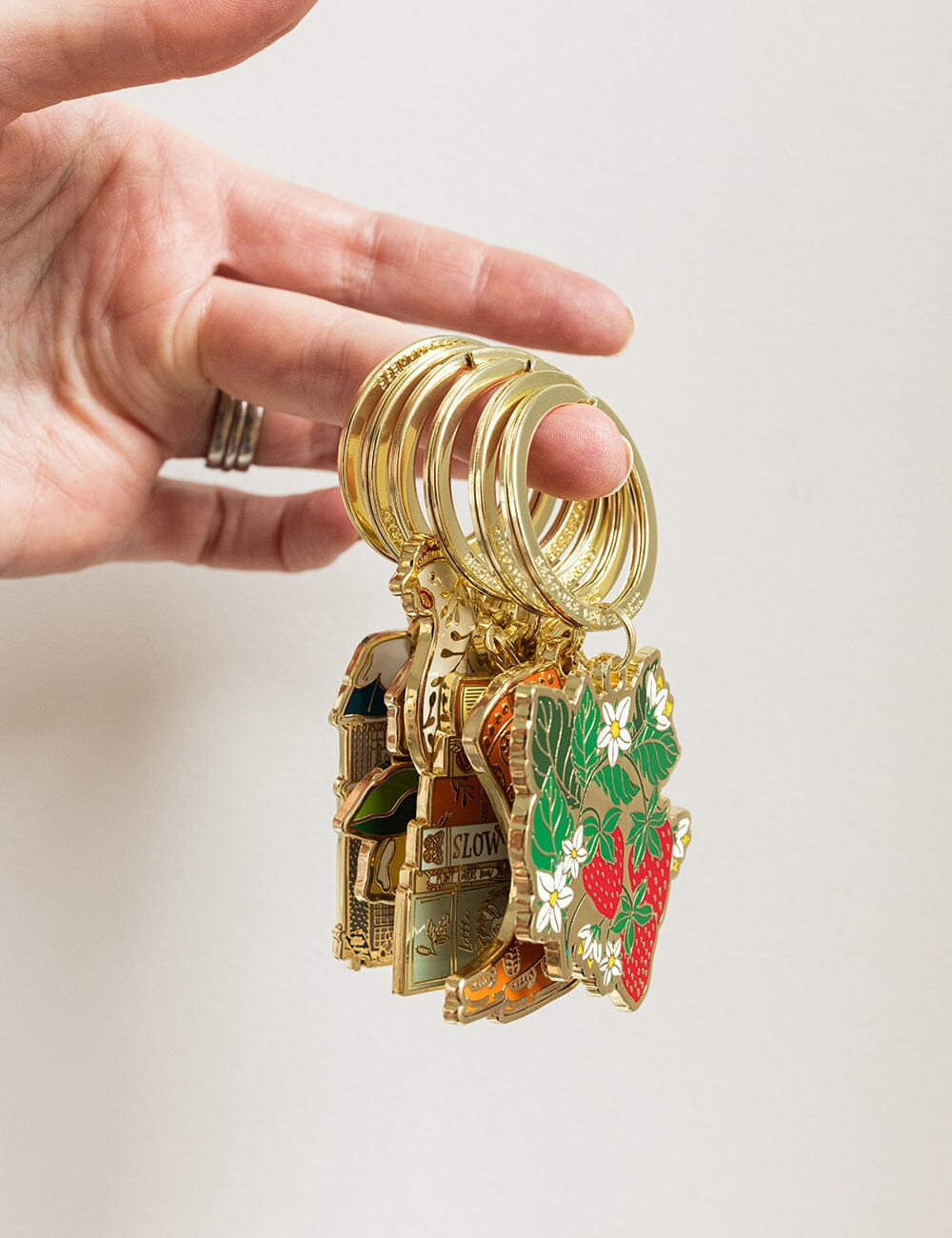 Gold keychain with various charms held by a hand on a light background