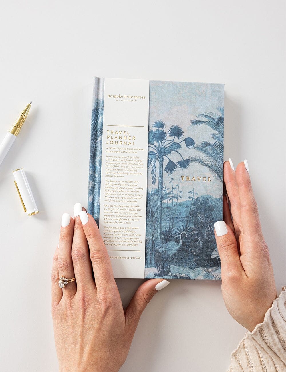 Person holding a travel planner journal with a scenic cover on a light background