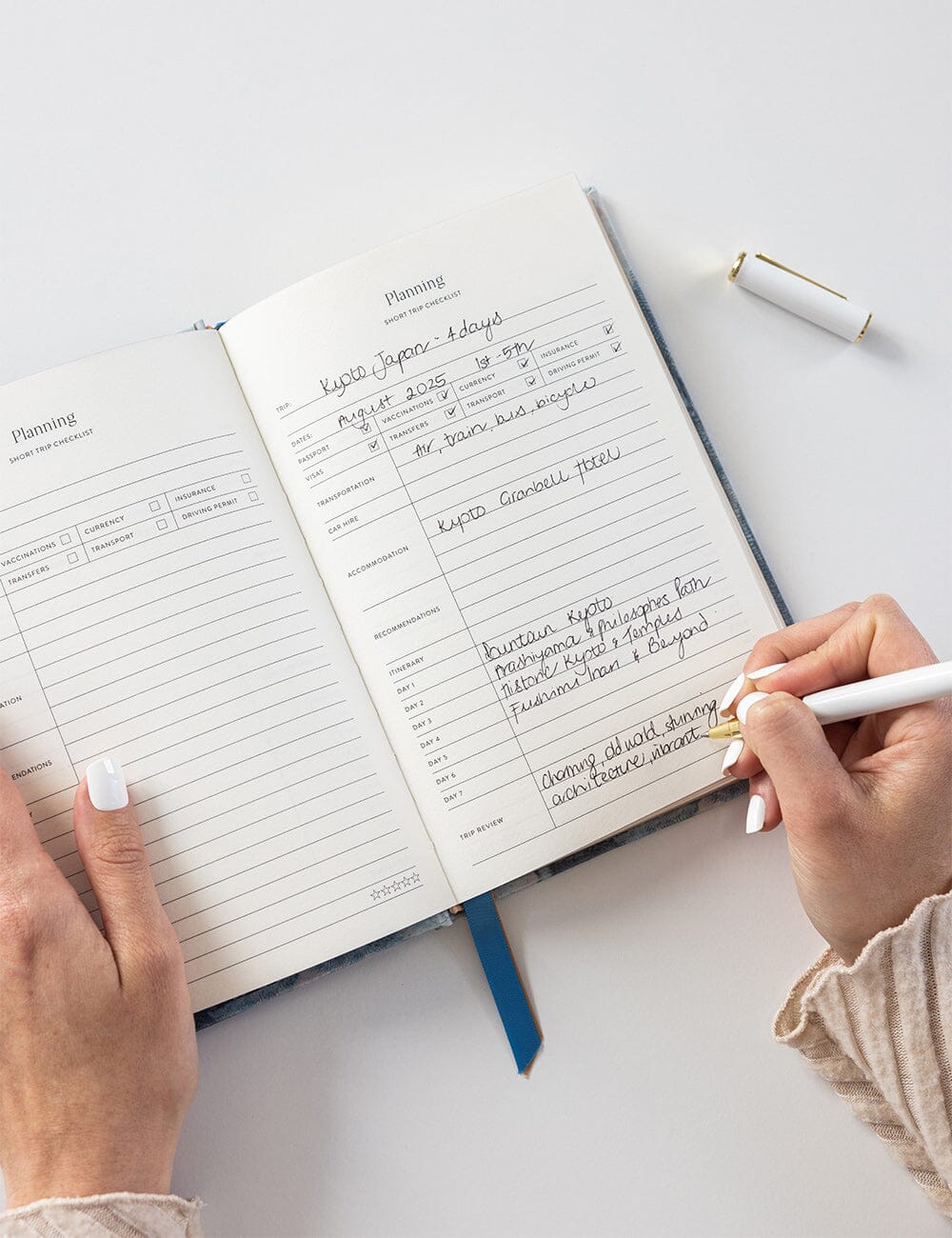 Person writing in a planner with a pen on a light surface