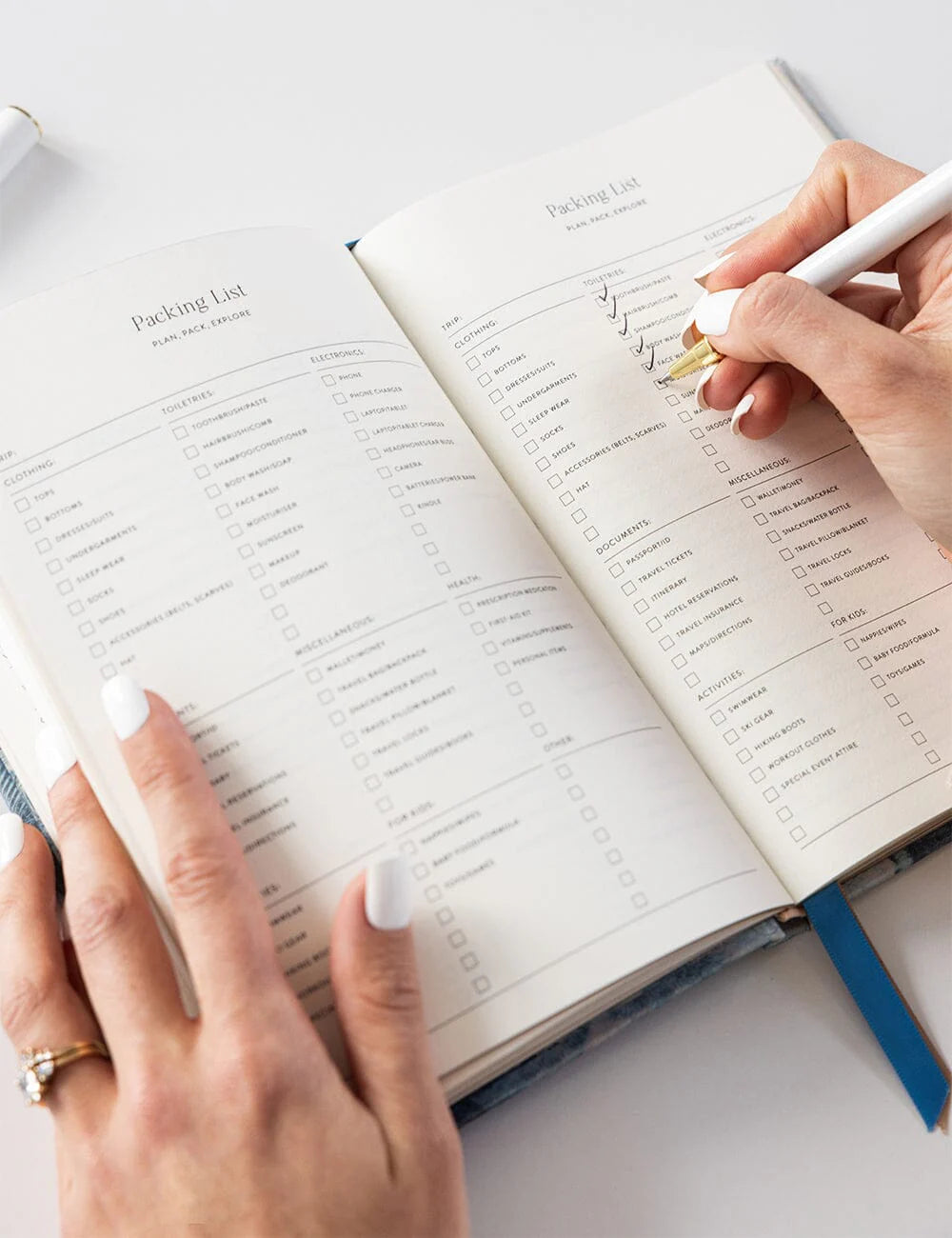 Person writing in a planner with a pen on a white surface