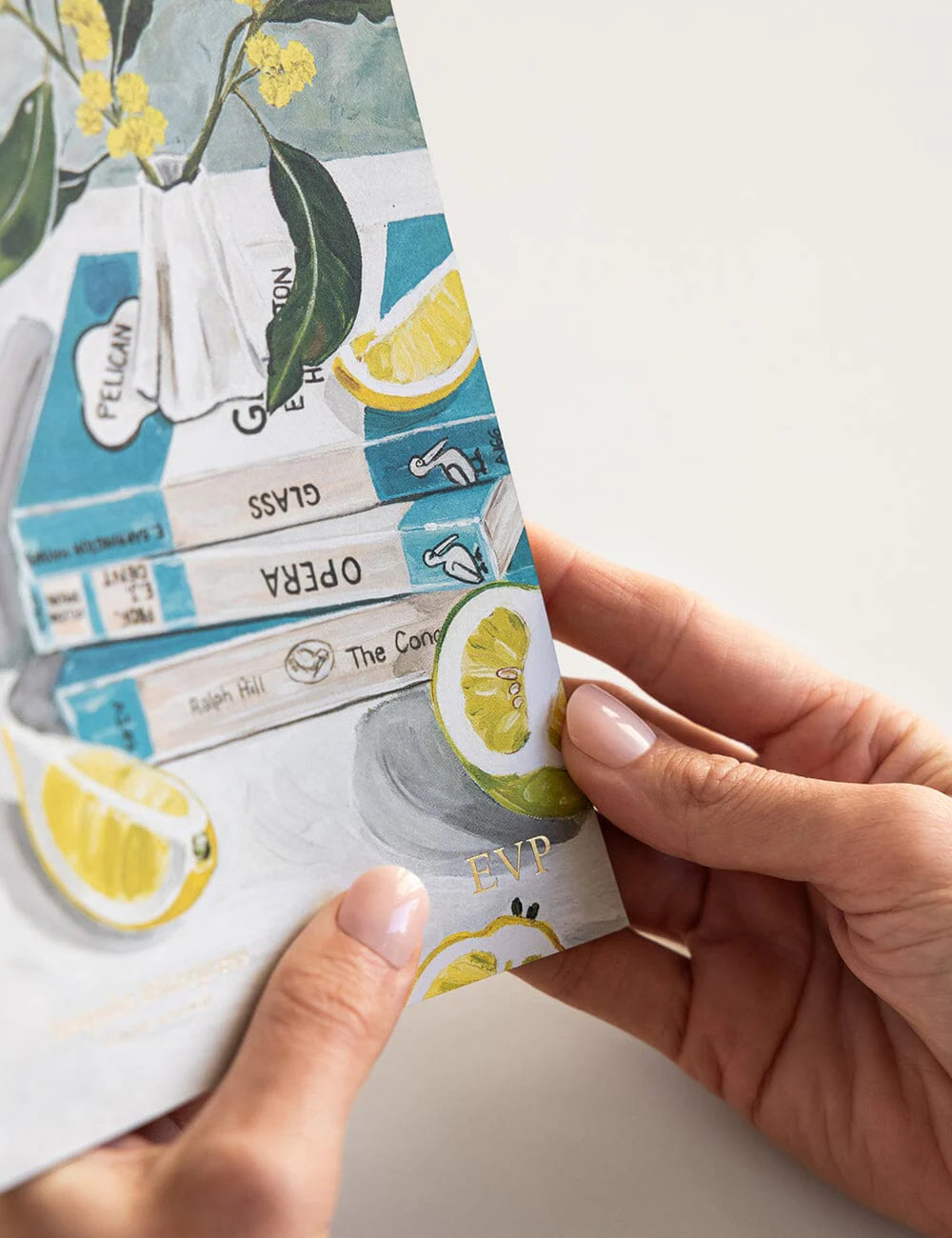 Hand holding a small notebook with lemon illustrations on a light background