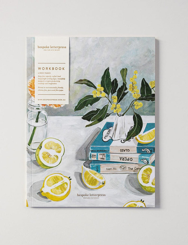 Workbook with a design of lemons, a vase with flowers, and books on a table.