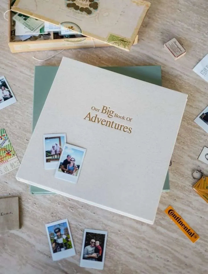 Album titled 'Our Big Book of Adventures' with photos on a wooden surface