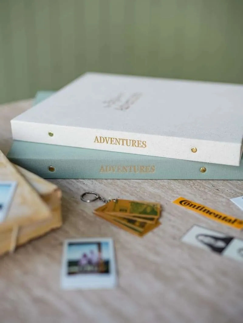 Album titled 'Adventures' with photos and a keychain on a wooden surface