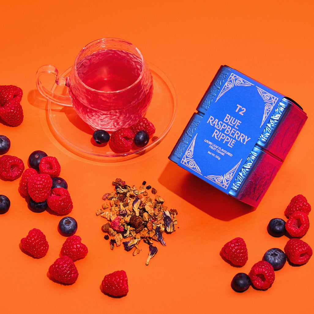 Tea packaging with a cup of tea, berries, and tea leaves on an orange background