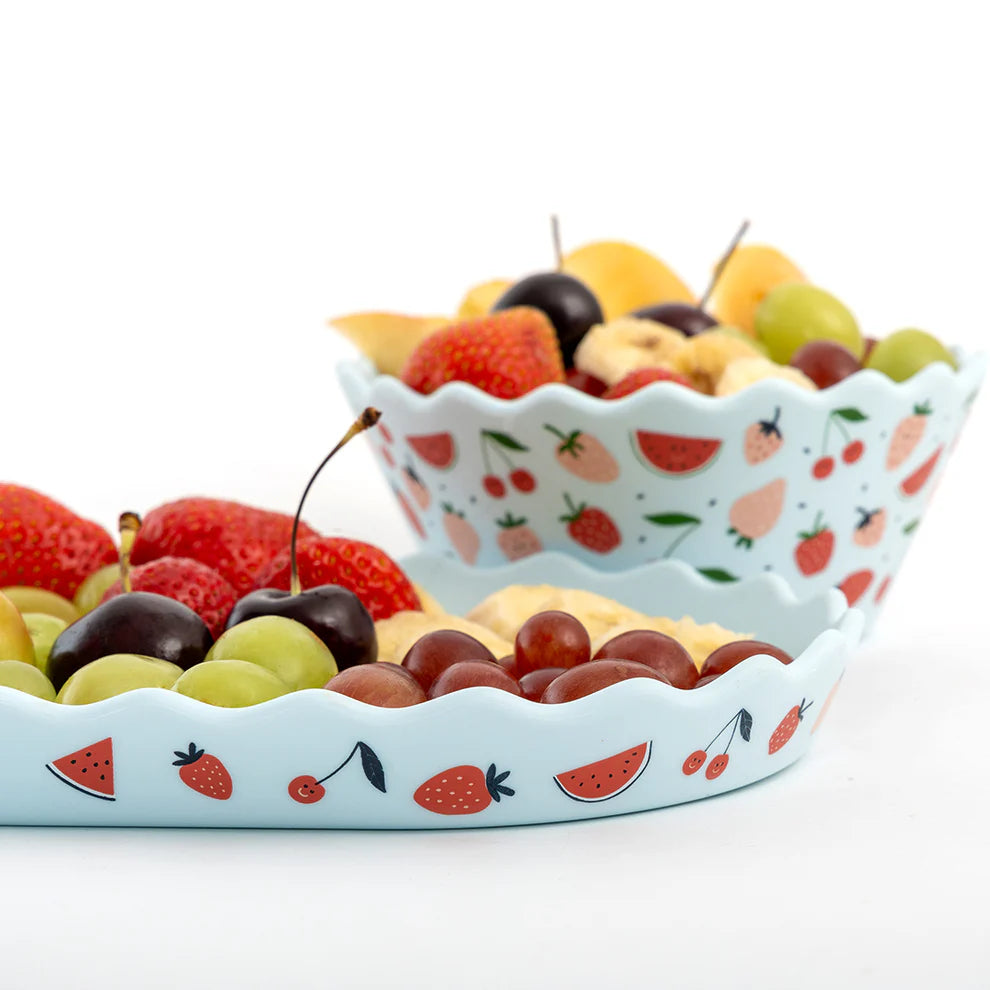 Fruit platter with a decorative bowl featuring fruit patterns on a white background