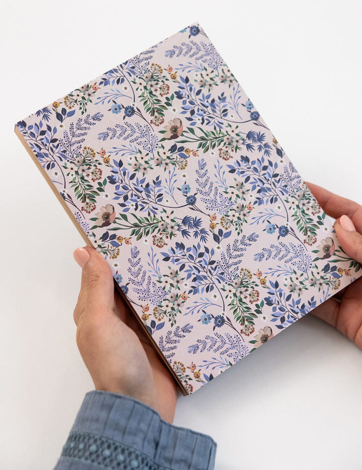 Floral patterned notebook held by a person on a white background