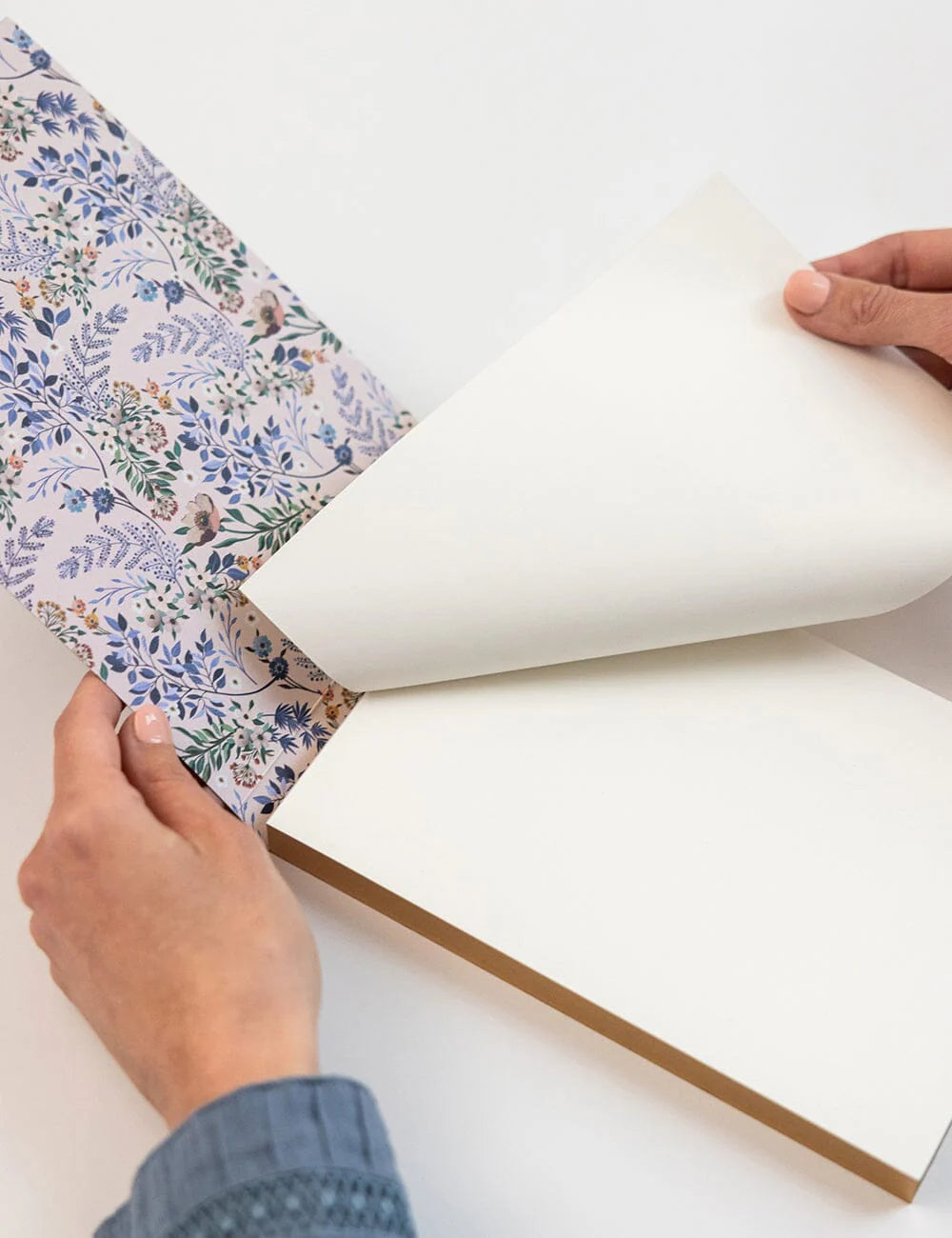 Person ripping off a piece of paper from a notepad on a white surface