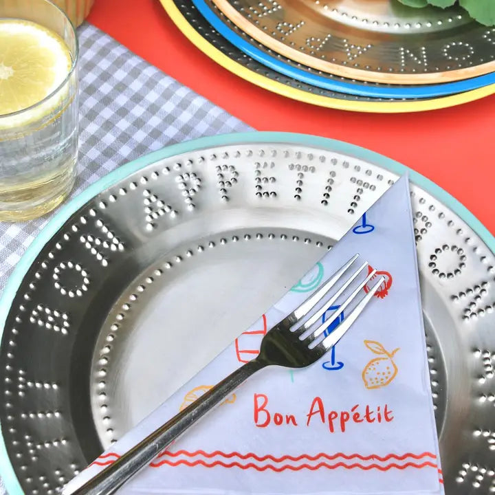 Decorative plate with a fork and 'Bon Appétit' napkin on a colorful table setting.