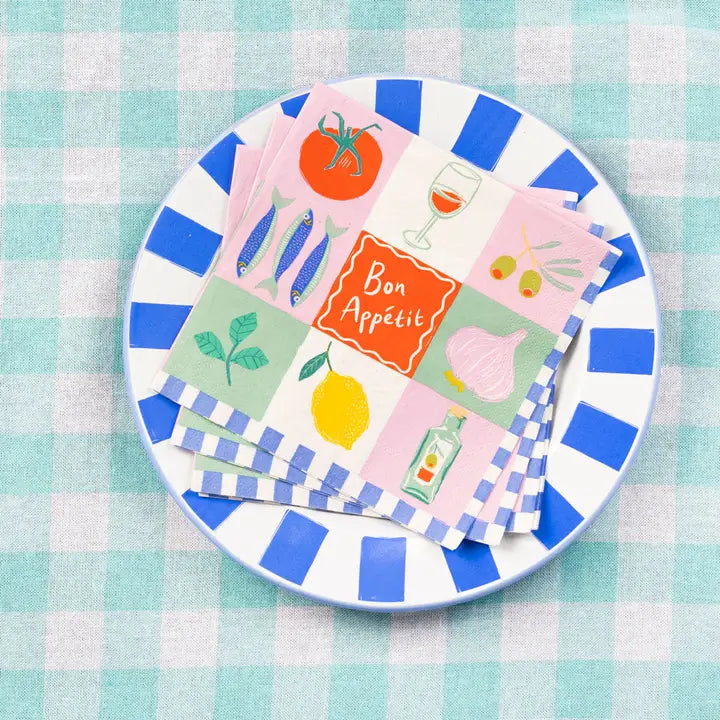Set of colorful paper napkins with illustrations on a striped plate over a checkered tablecloth.