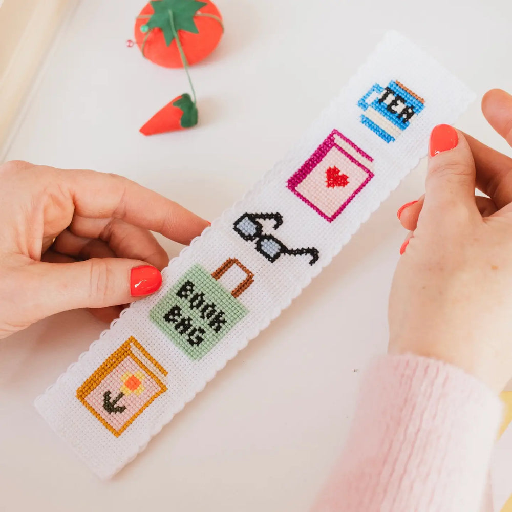 Cross-stitching project with cartoon-themed designs on a white fabric.