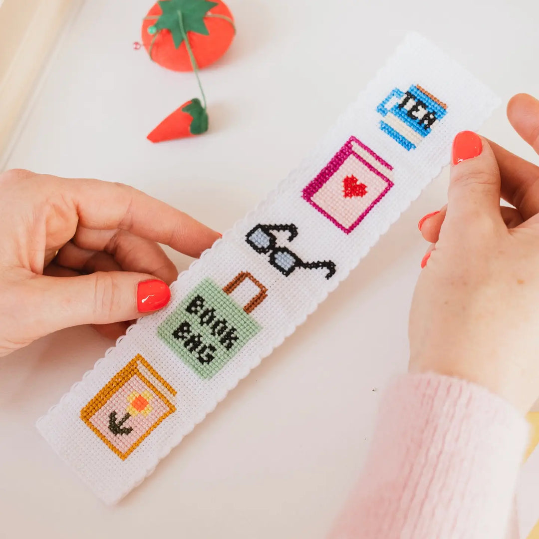Cross-stitching project with cartoon-themed designs on a white fabric.