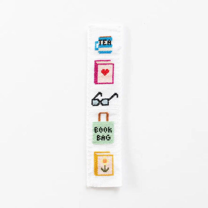 Cross-stitched design with various book-themed icons on a white background