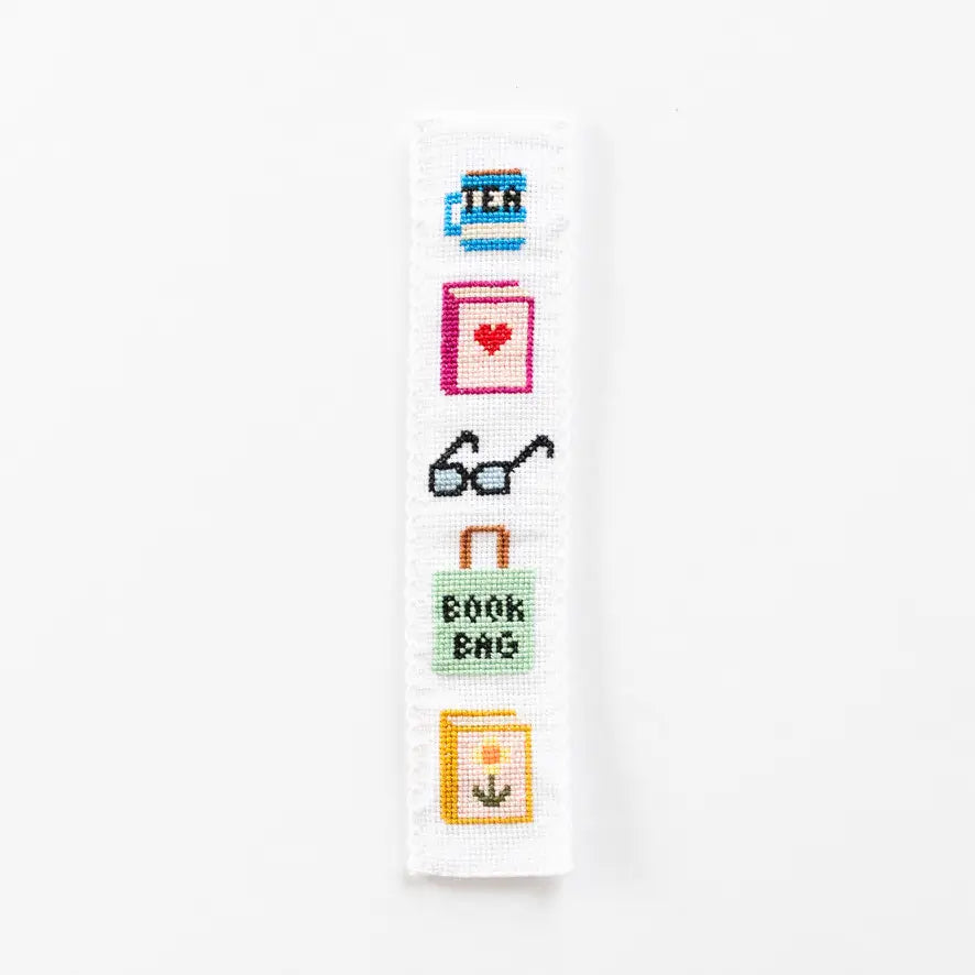 Cross-stitched design with various book-themed icons on a white background