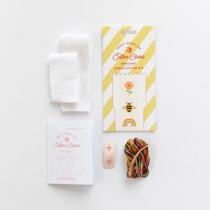 Cotton Clara cross-stitch kit with packaging, thread, and needle on a white background