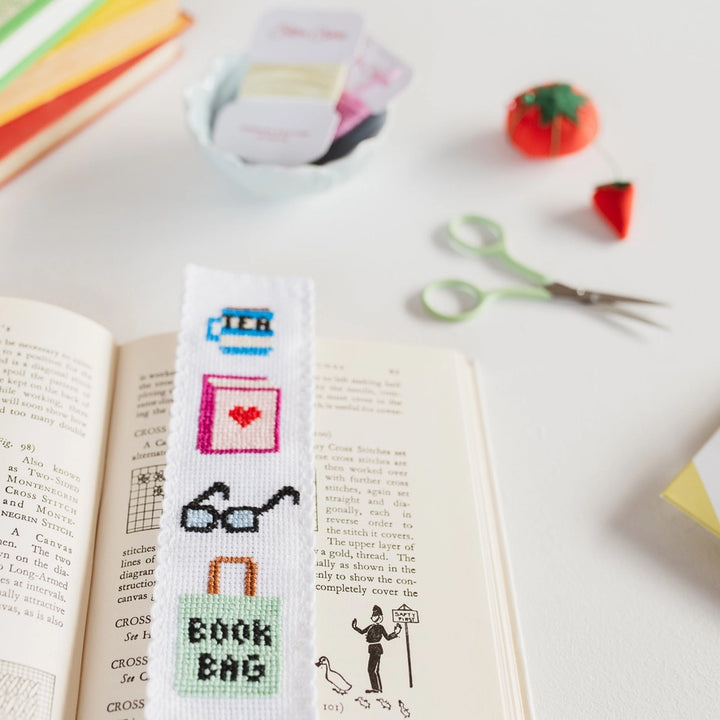 Cross-stitched bookmark with various designs on an open book