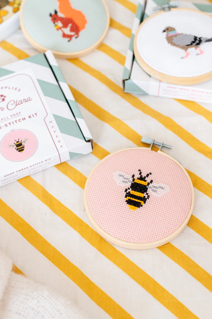 Embroidery hoop with bee design on a striped fabric background