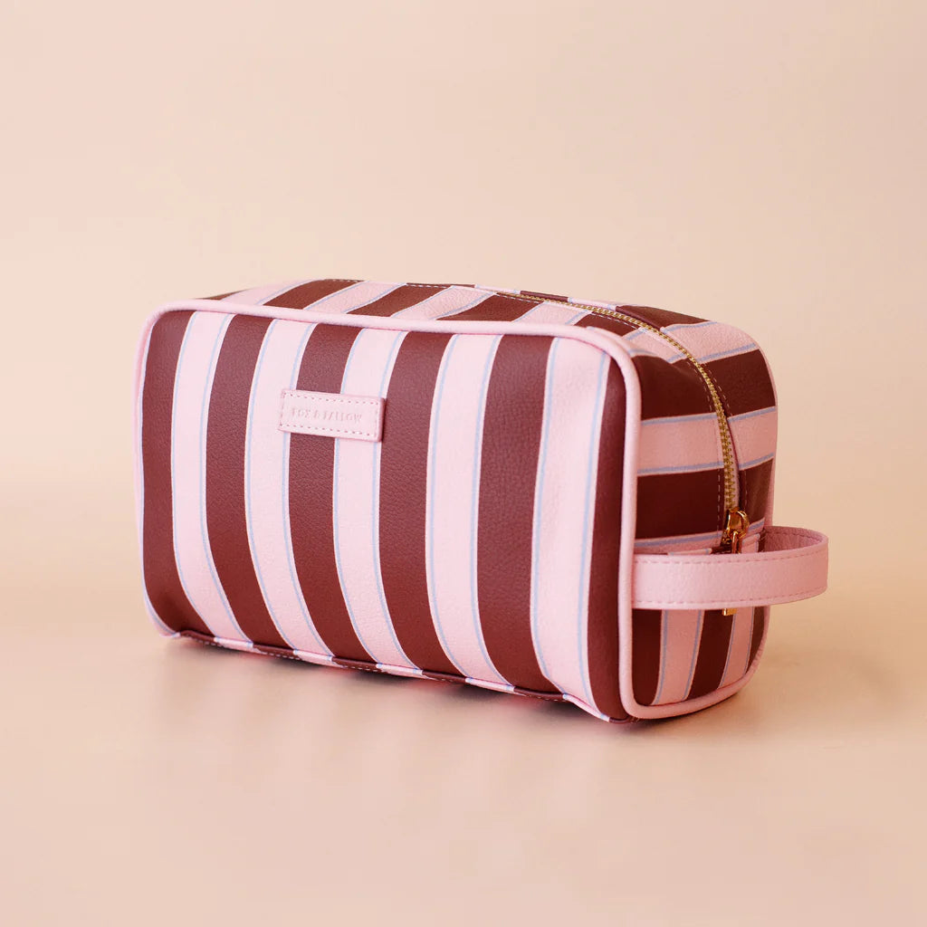 Striped toiletry bag with pink and brown stripes on a beige background