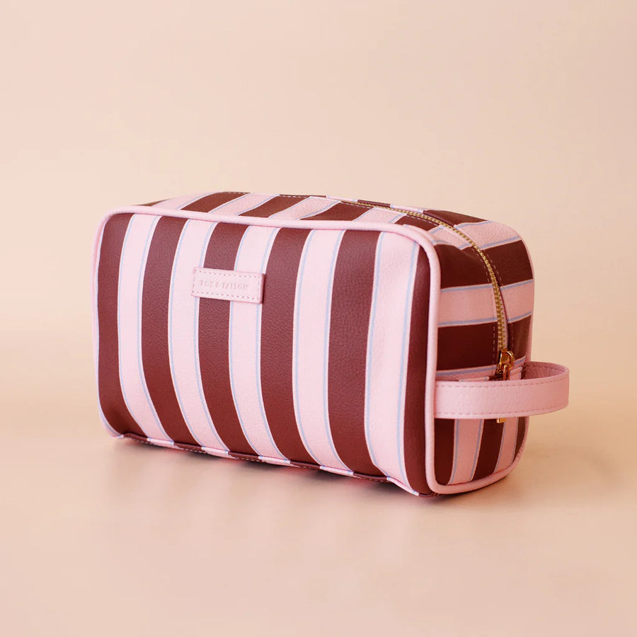 Striped toiletry bag with pink and brown stripes on a beige background