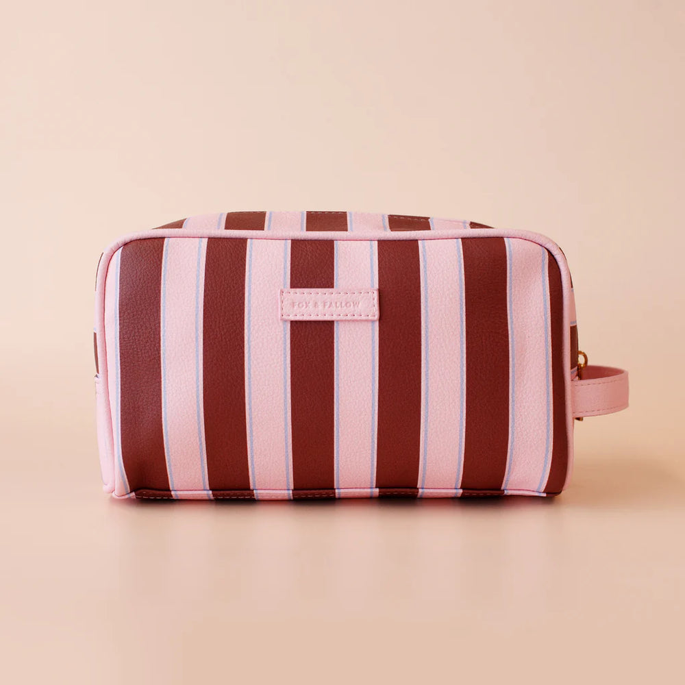 Striped toiletry bag with pink and brown stripes on a beige background