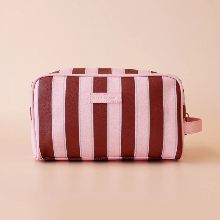 Striped toiletry bag with pink and brown stripes on a beige background