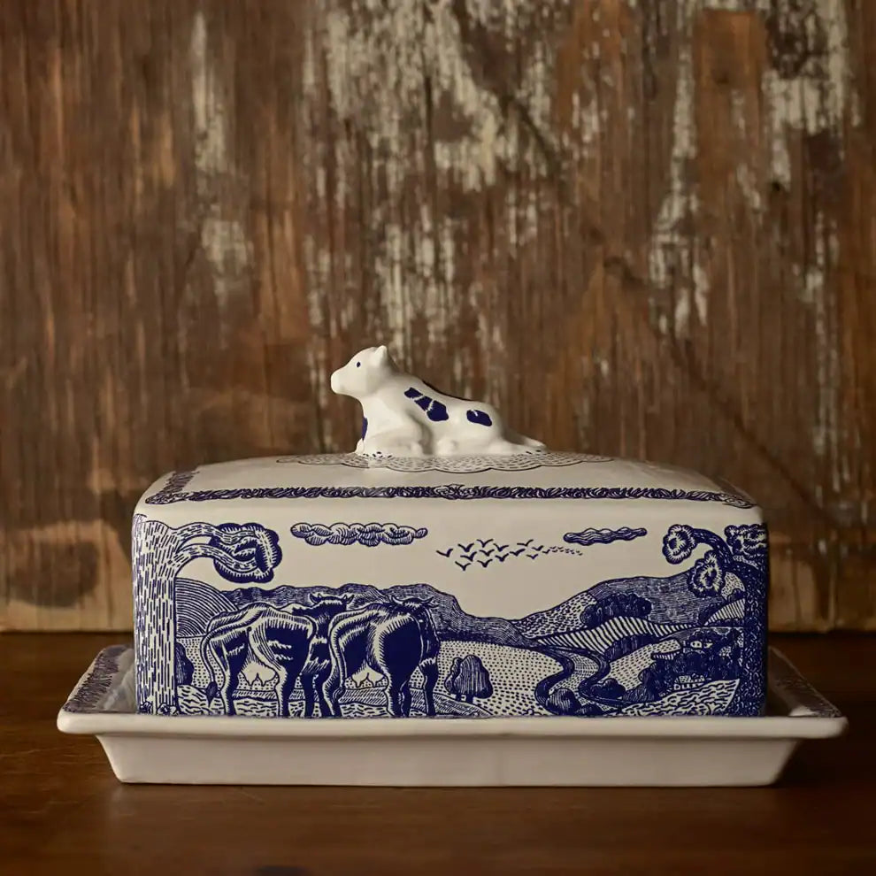 Butter dish with blue design and white cow lid on a wooden surface