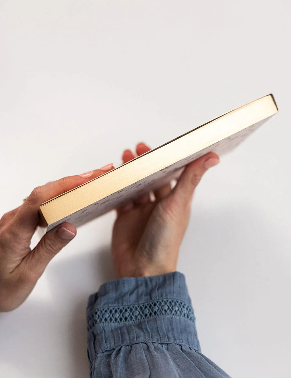 Person holding a gold and white rectangular notepad against a white background