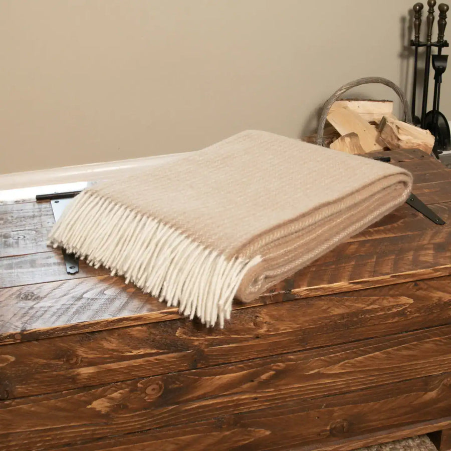 Beige throw blanket on a wooden surface with a neutral background