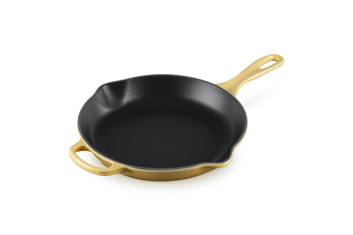Black cast iron skillet with yellow enamel on outside on a white background
