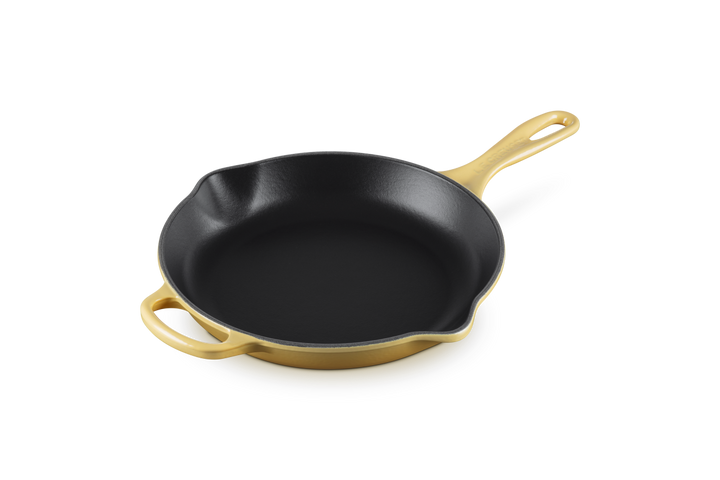 Black cast iron skillet with yellow enamel on outside on a white background