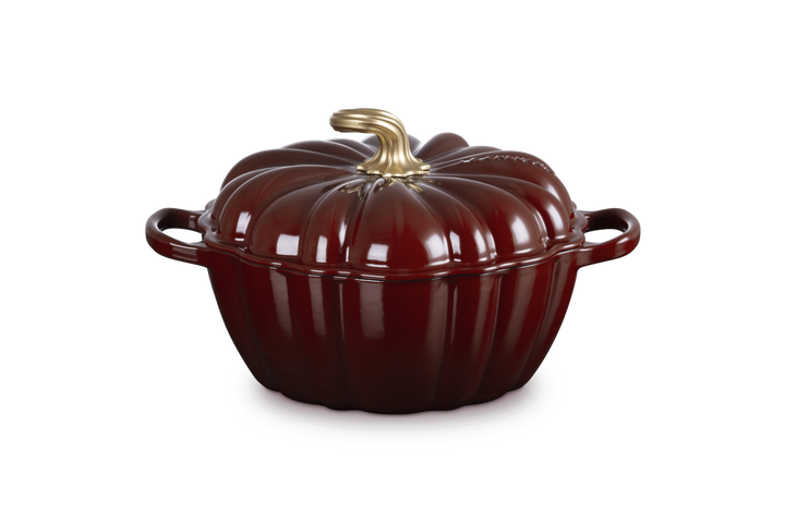 Red pumpkin-shaped cookware with a gold handle on a white background