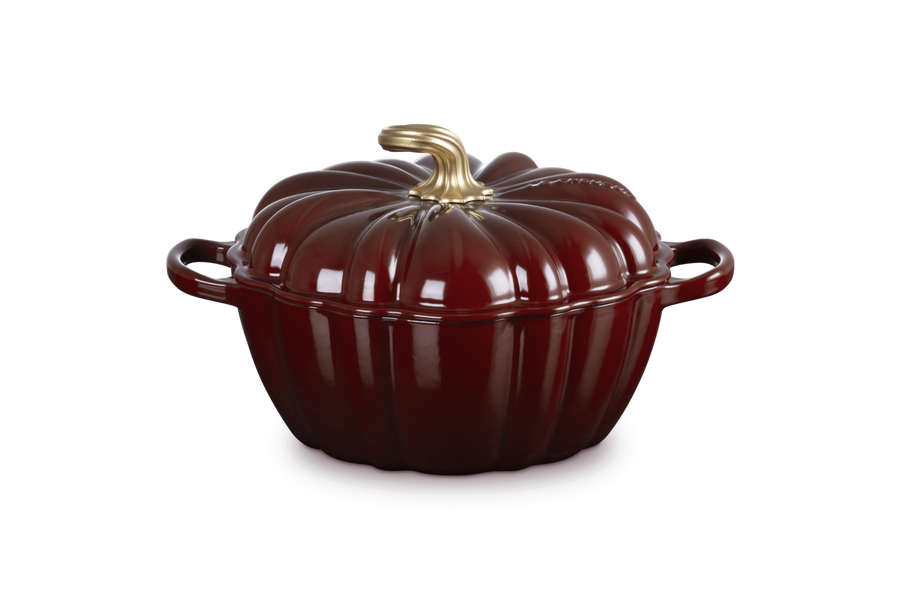 Red pumpkin-shaped cookware with a gold handle on a white background