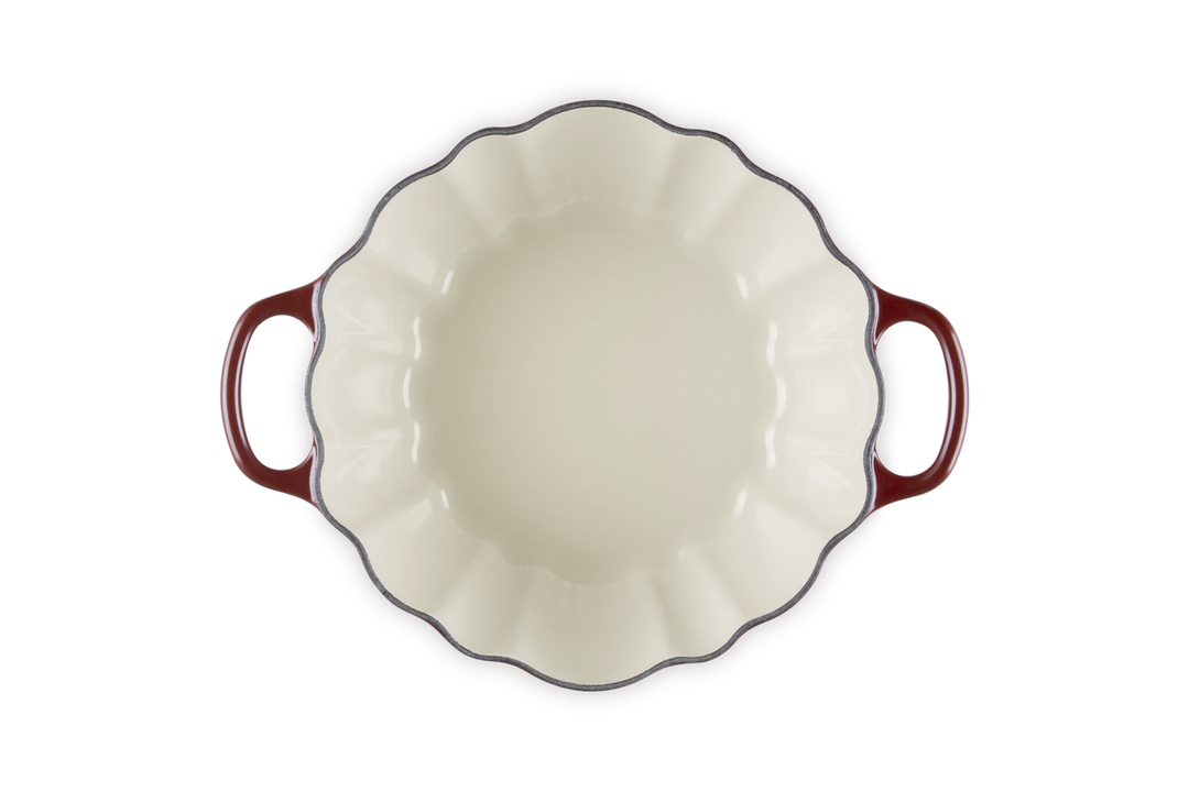 White ceramic pie dish with red handles on a white background