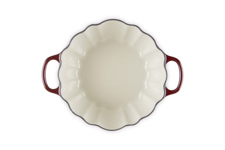 White ceramic pie dish with red handles on a white background