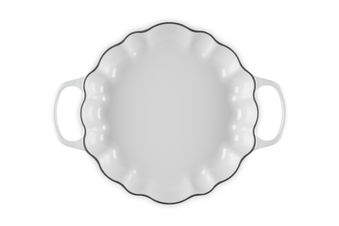 A white baking dish with a scalloped rim and two side handles, shown from a top-down view on a white background.