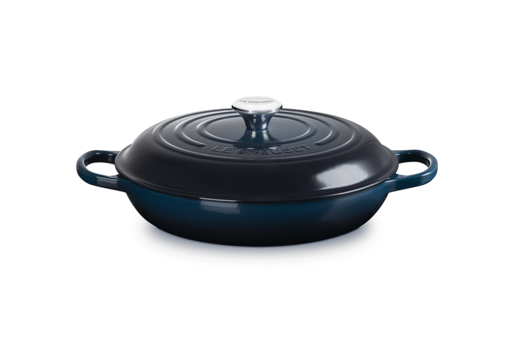 Blue enameled cast iron skillet with lid on a white background