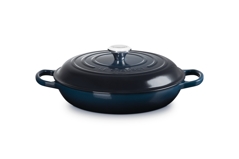 Blue enameled cast iron skillet with lid on a white background