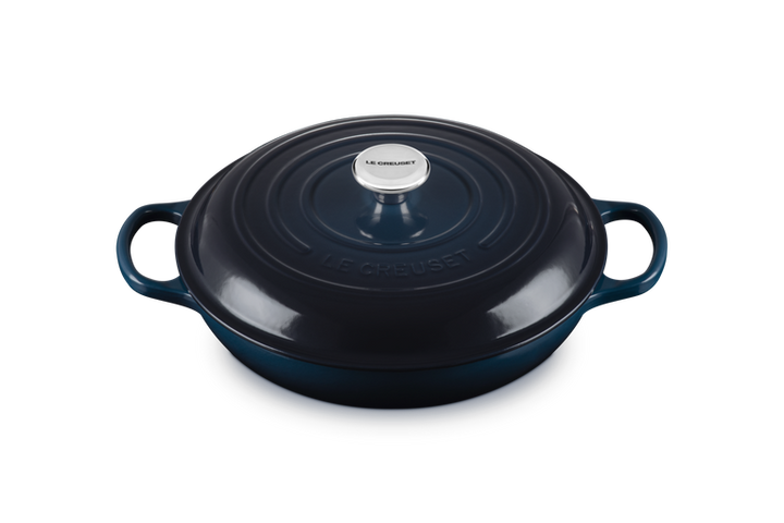 Dark blue enameled cast iron round Dutch oven with handles on a white background