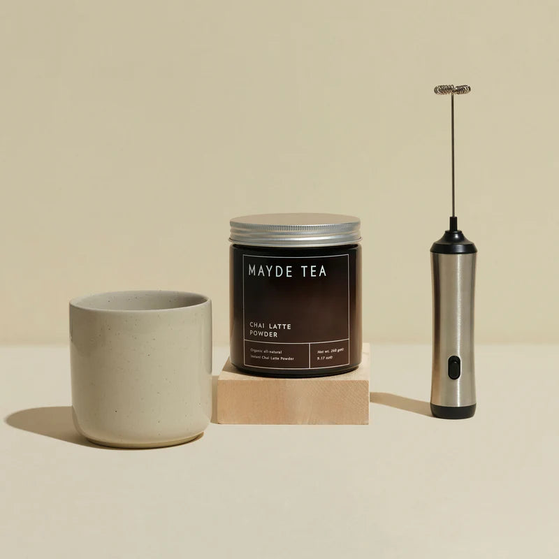 Mayde Tea canister with a ceramic cup and milk frother on a beige background