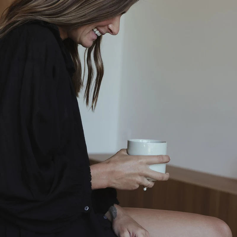 Person holding a white cup in a neutral setting
