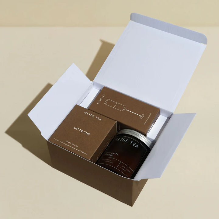 Box containing a 'Mayde Tea' latte cup on a beige background