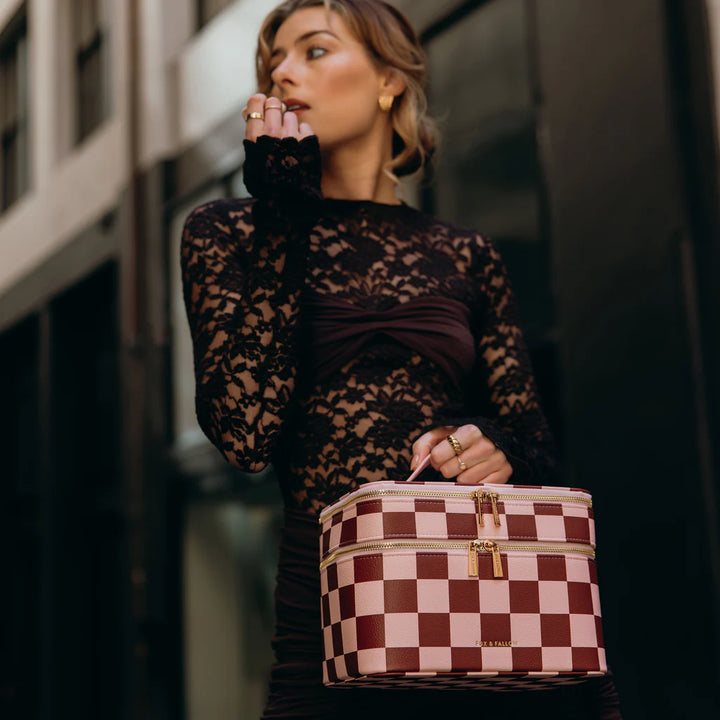 Woman holding a checkered vanity case in an urban setting