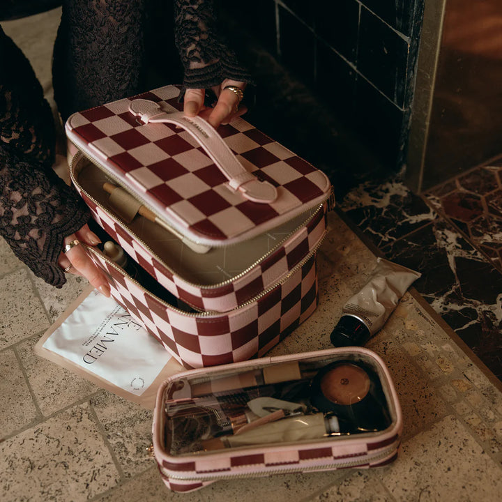 Person holding a checkered makeup case on a marble surface